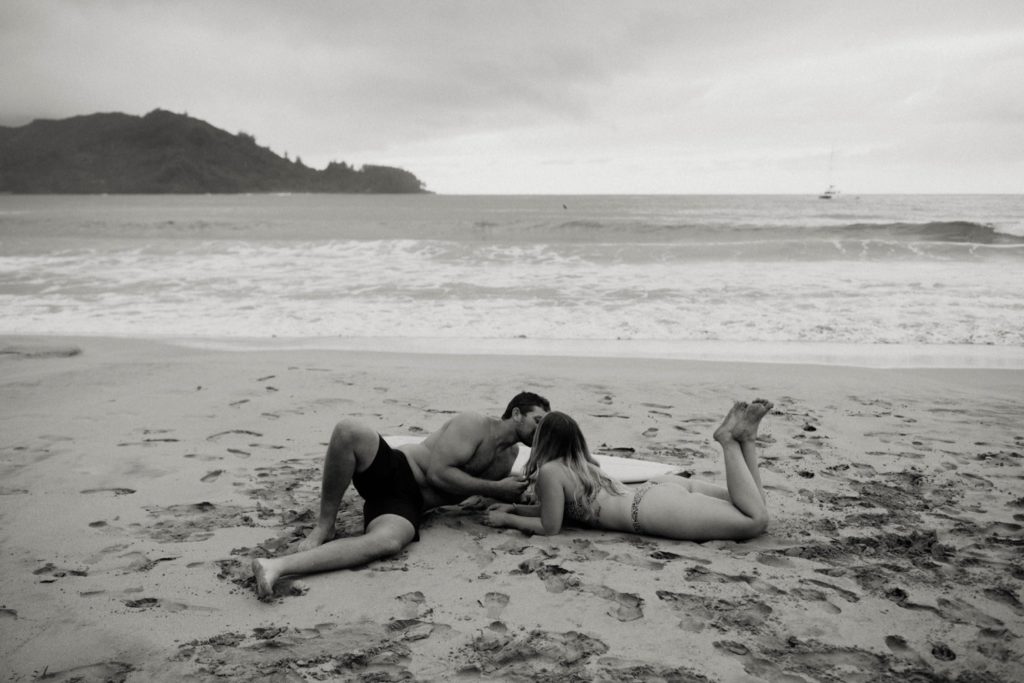 couple laying on the beach kissing
