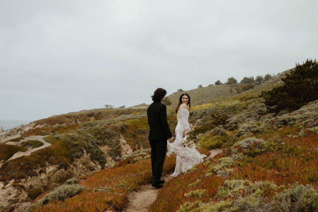 Wedding couple hiking and holding dress 