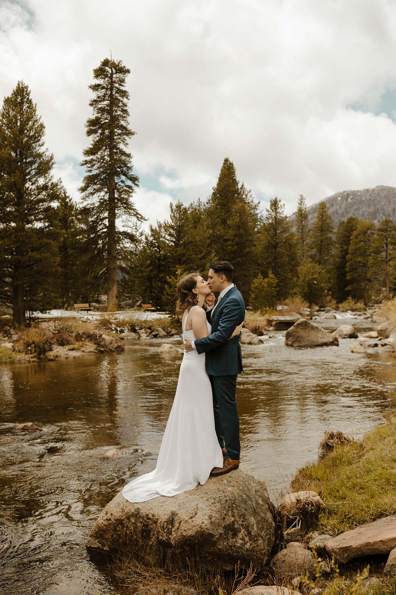 wedding couple kissing on a rock by the lake