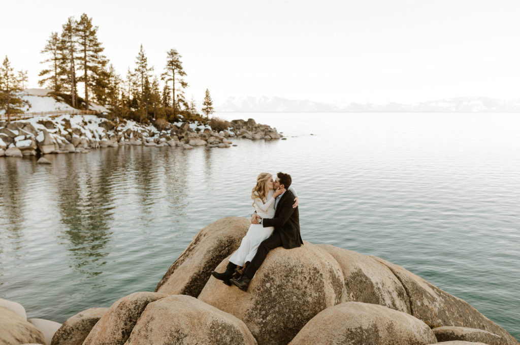 elopement couple kissing on a rock overlooking Lake Tahoe in the winter