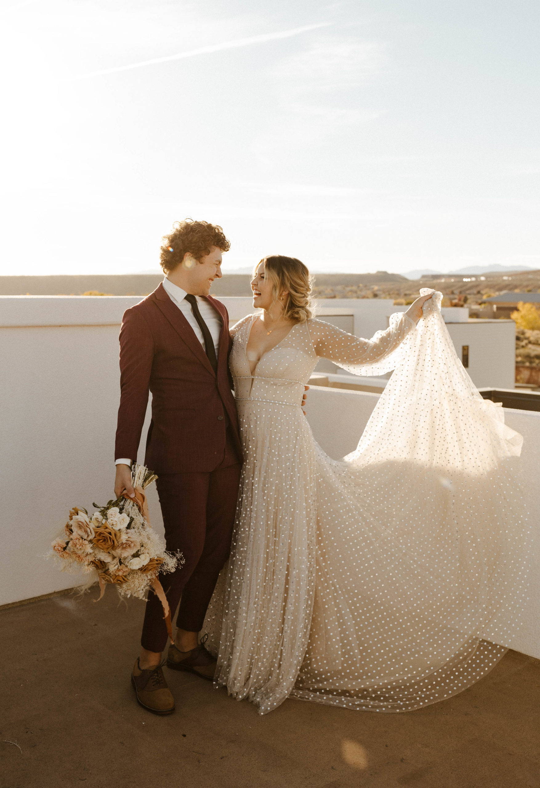 wedding couple playing with dress on rooftop