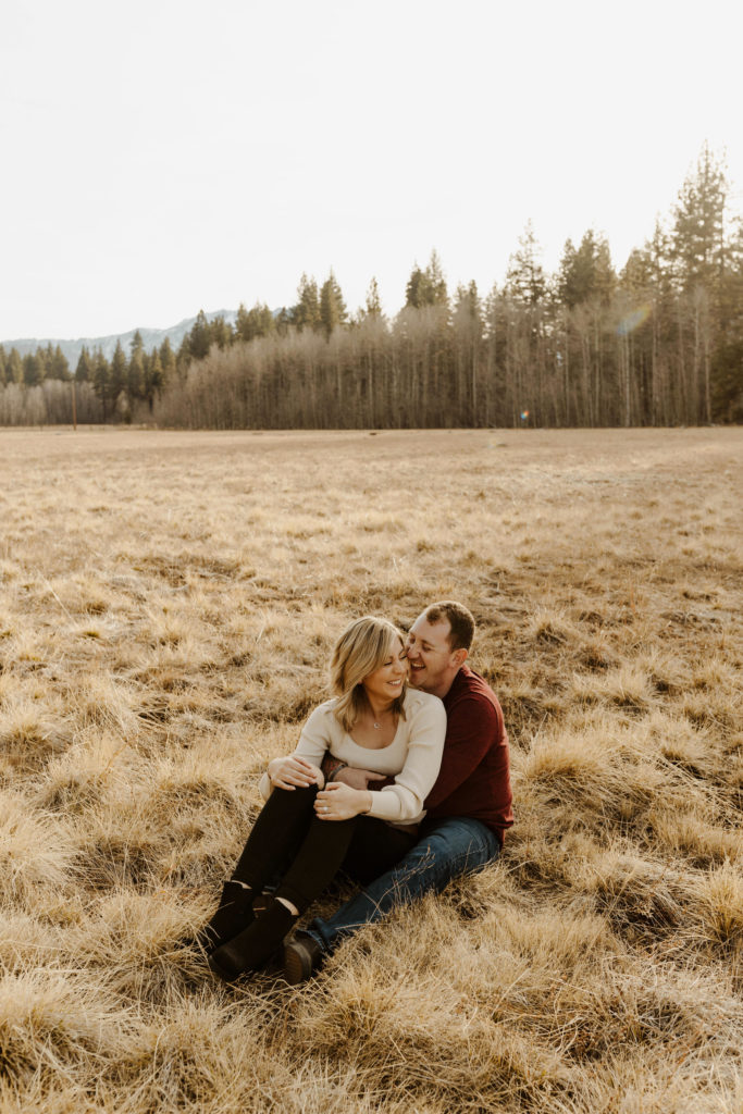 couple sitting in a golden meadow together in the fall
