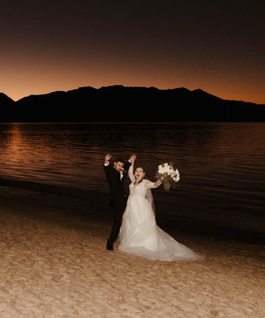 wedding couple cheering on the beach at sunset