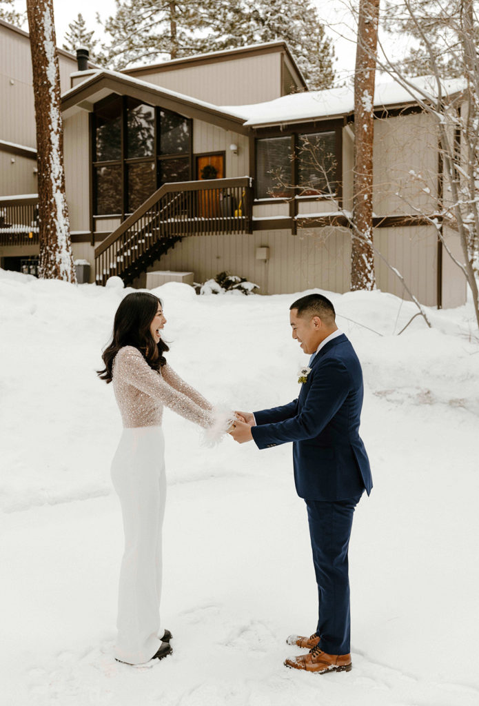 winter wedding couple standing in the snow smiling