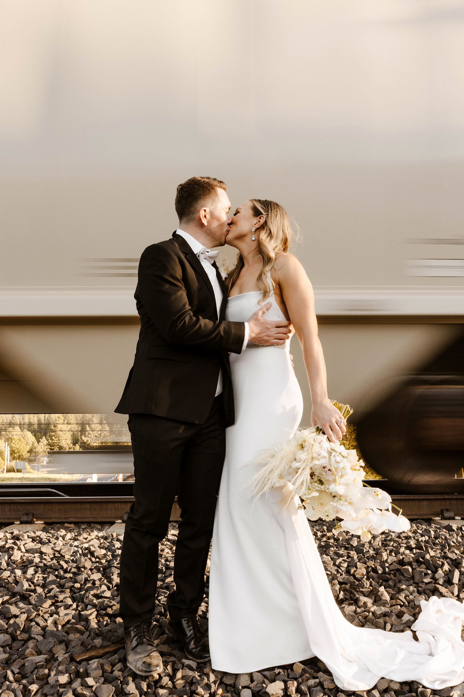 bride and groom kissing in front of a moving train