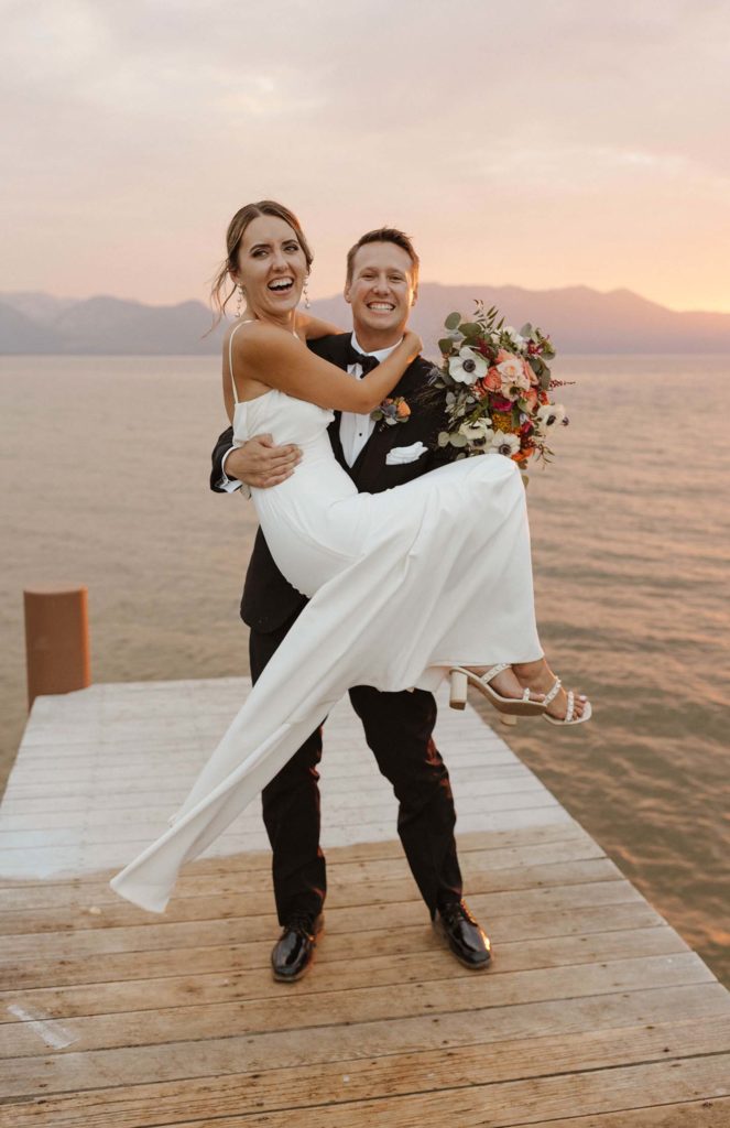 groom holding bride on a dock in lake tahoe at sunset