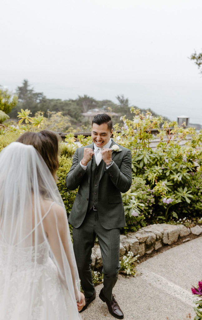 Wedding groom celebrating during first look with bride on stone walkway at the carmel highlands