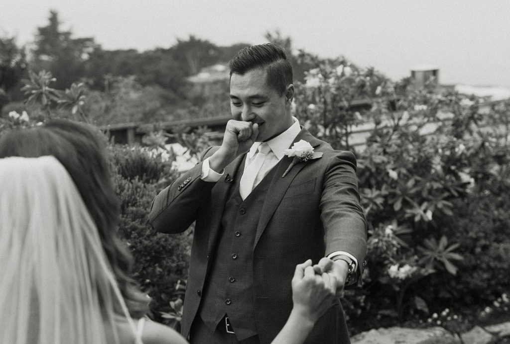 Wedding groom emotional while holding brides hand during first look at the carmel highlands