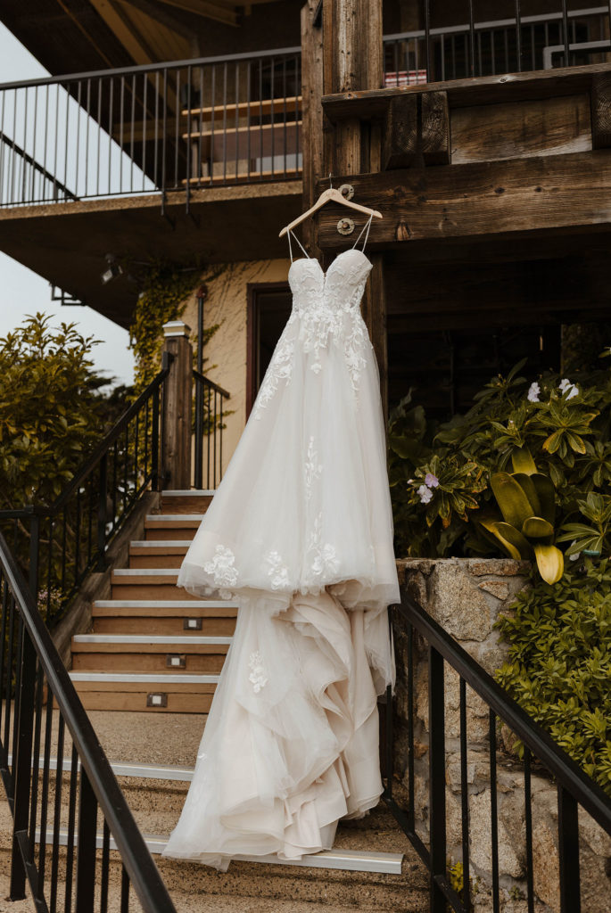 Wedding dress hanging from wooden beam over stairs at carmel highlands