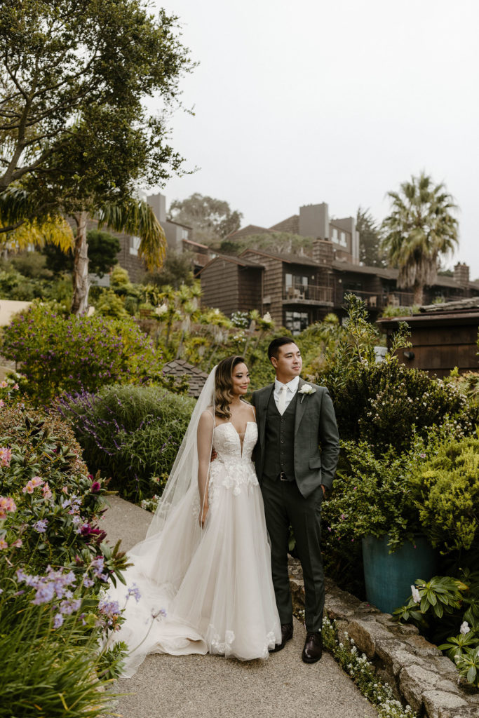 Wedding couple standing together with arms around each other on stone walkway at the carmel highlands