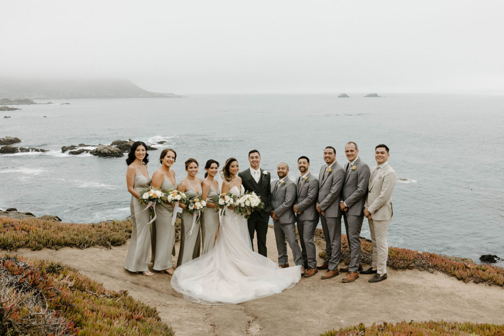 Wedding couple and bridal party smiling and standing together looking at camera with lake in background at carmel highlands