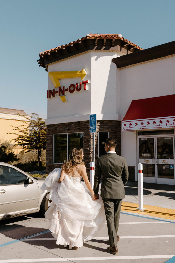 Wedding couple holding hands while walking into in-n-out together