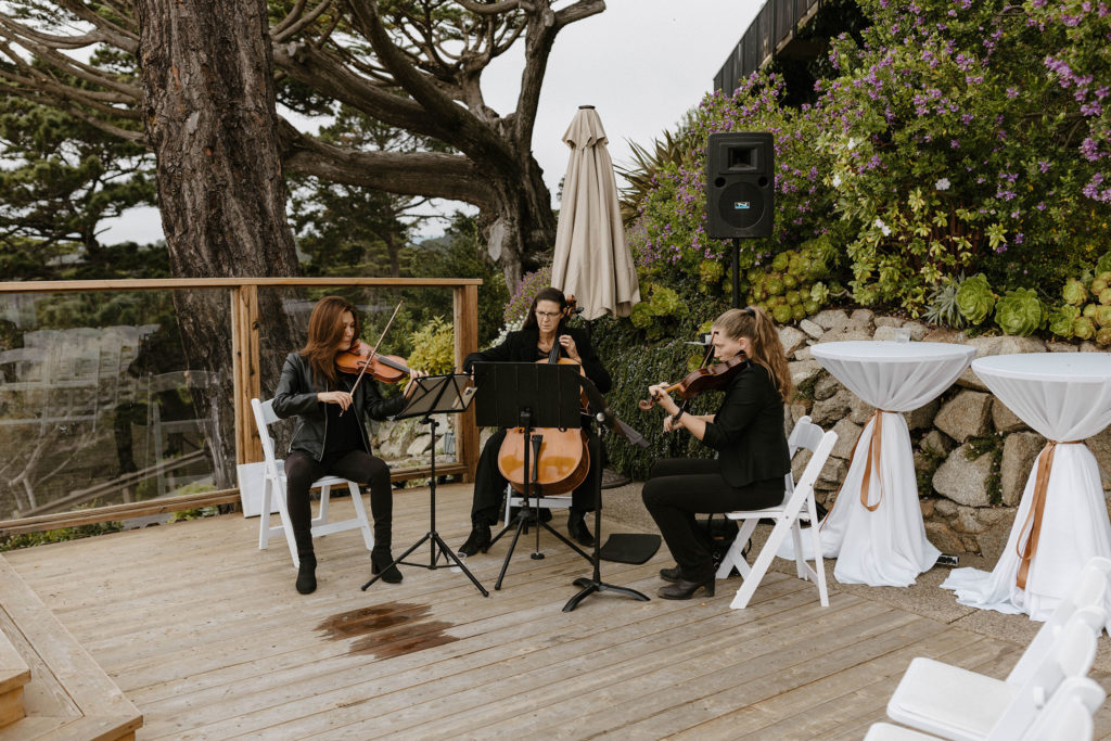 Musicians playing instruments while sitting on white chairs on wooden balcony at carmel highlands