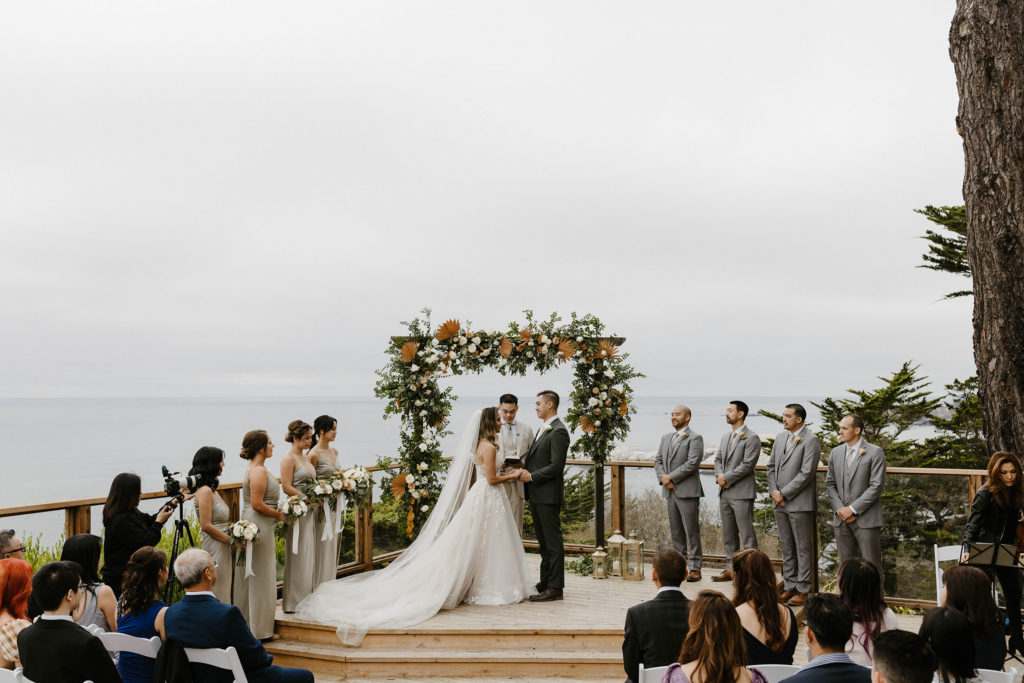 Wedding couple holding hands during wedding ceremony at Carmel Highlands with lake in background