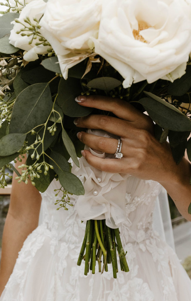 Close up of wedding brides hands with ring on finger holding flower bouquet at carmel highlands
