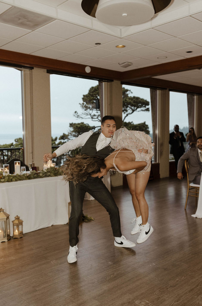 Wedding groom flipping bride over while on dance floor during reception at carmel highlands