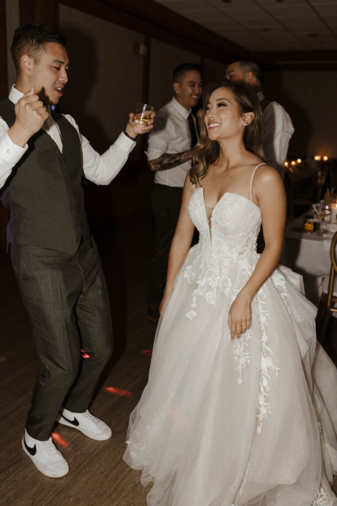 Wedding couple smiling and dancing while groom holds drink during reception at carmel highlands