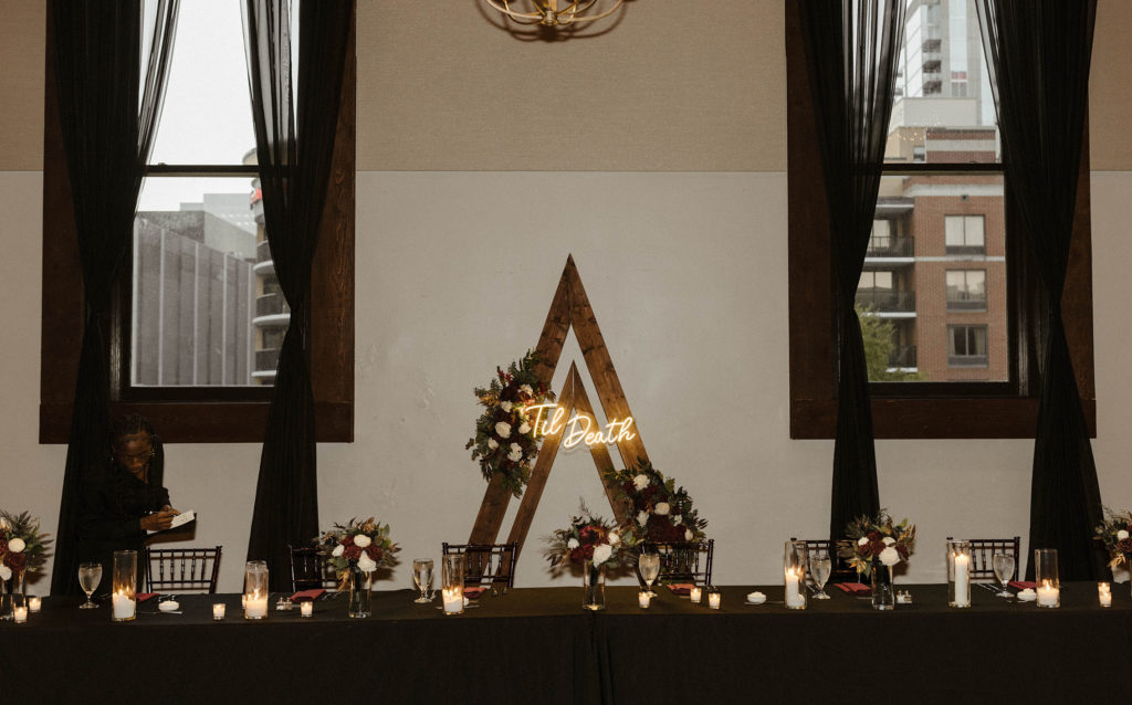 Wedding party dinner table with arch in background with illuminated words inside at the Bell Tower