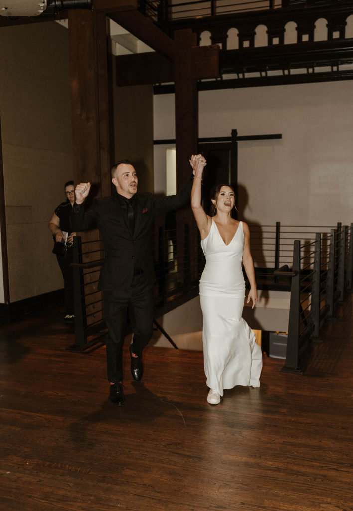 Wedding couple holding hands and celebrating while walking in during grand entrance inside in the Bell Tower