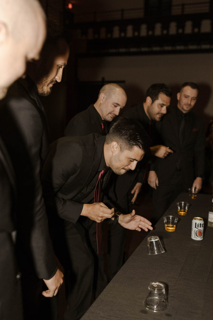 Groomsmen playing flip cup during reception at the Bell Tower