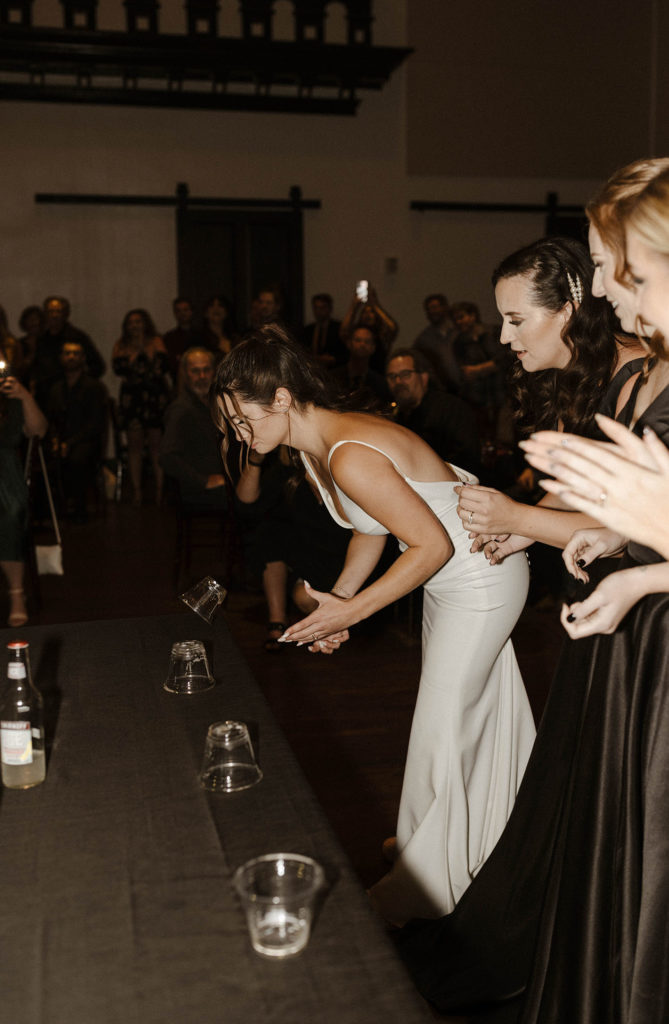 Wedding bride and bridesmaids playing flip cup during reception at the Bell Tower