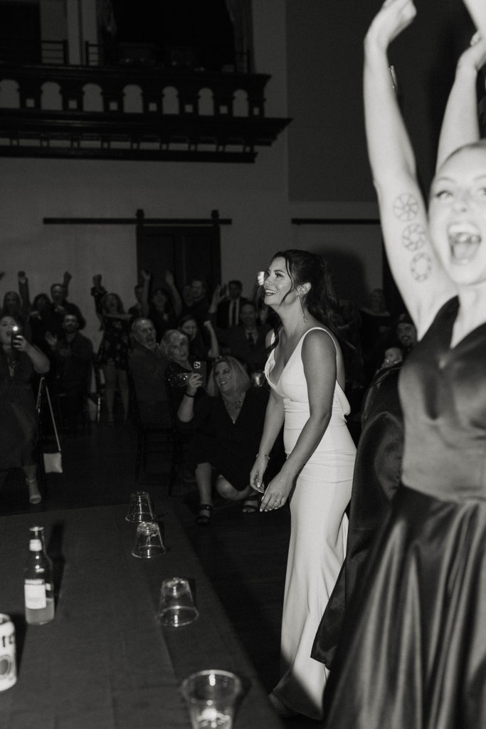 Wedding bride and bridesmaids laughing after winning at flip cup during reception at the Bell Tower