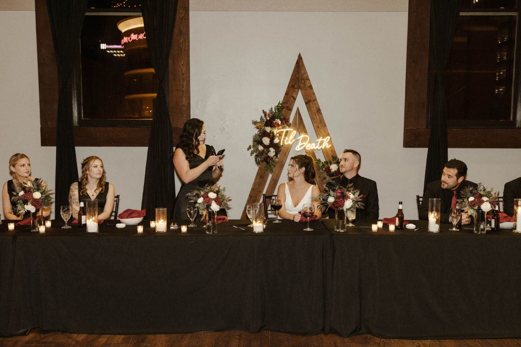 Bridesmaid standing and reading speech at dinner table during reception at the Bell Tower