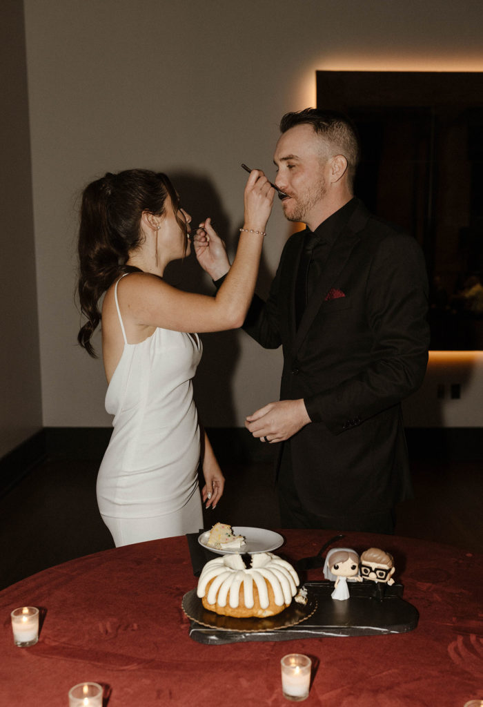Wedding couple feeding each other cake at same time during reception at the Bell Tower