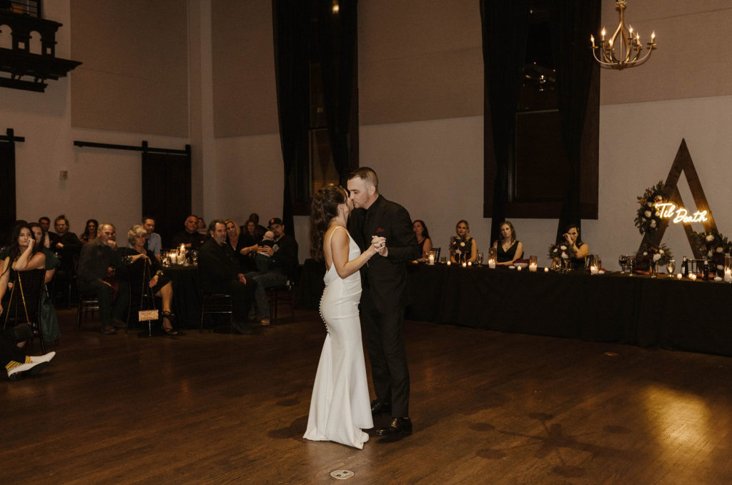 Wedding couple holding hands during first dance and kissing during reception at the Bell Tower