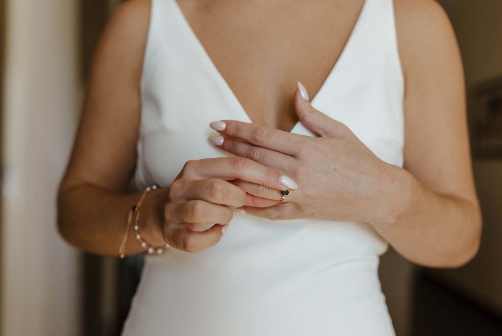 Close up of wedding brides hand putting ring on inside at the Bell Tower