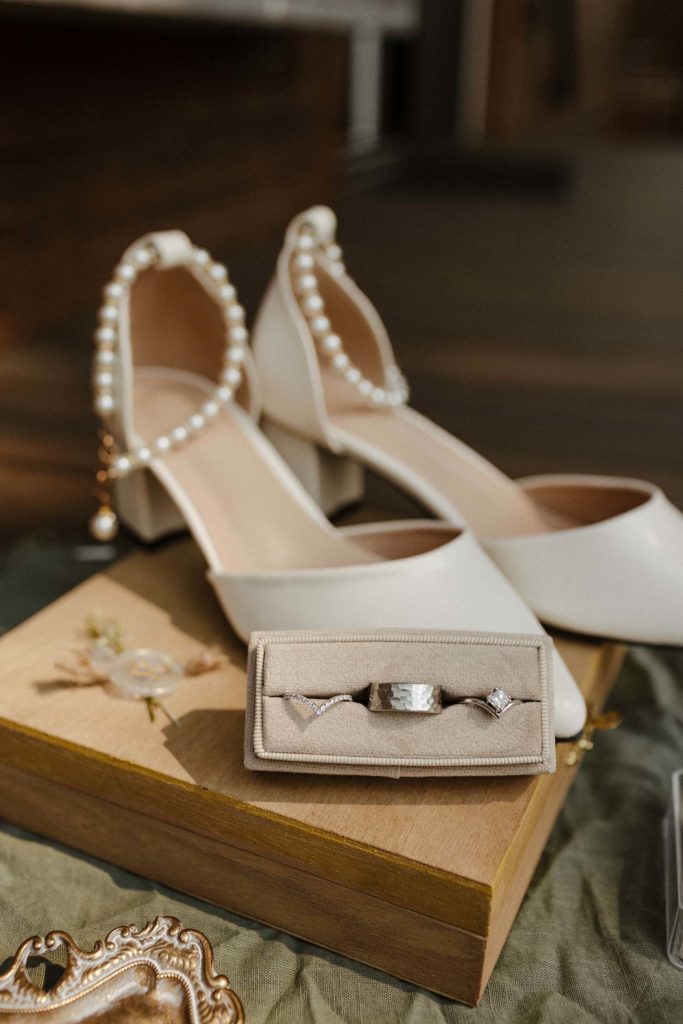 Close up of wedding ring in details flatlay with shoes in background at the elm estate