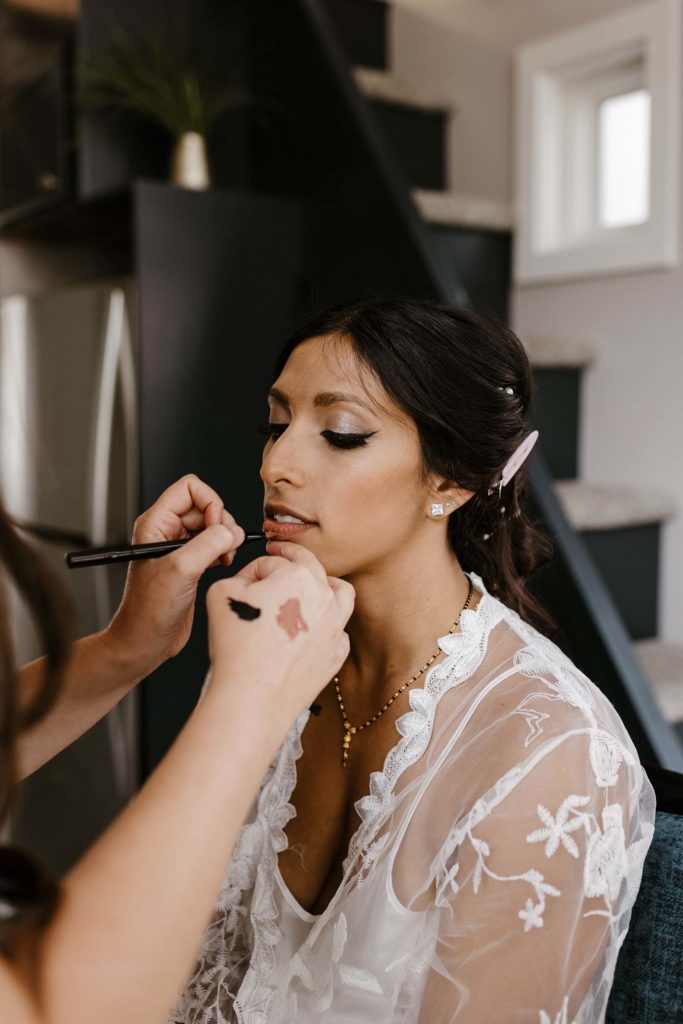 Wedding bride with eyes closed getting make up done by make up artist at the elm estate