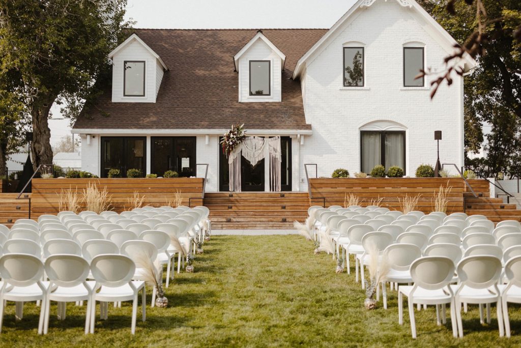 Overview of wedding ceremony outside at the elm estate with white building in background