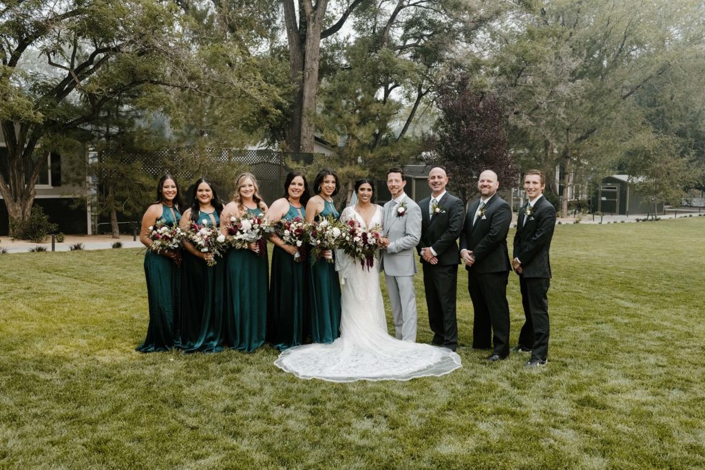 Wedding party and couple standing together and smiling at camera while outside at the elm estate
