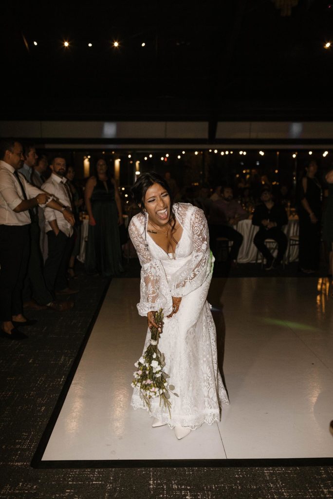 Wedding bride laughing while holding flower bouquet during reception at the elm estate