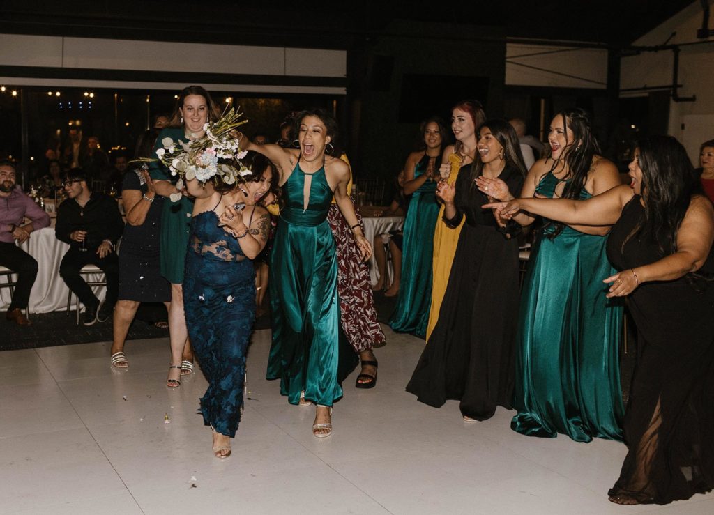 Bridesmaids fighting to catch brides flower bouquet during wedding reception at the elm estate