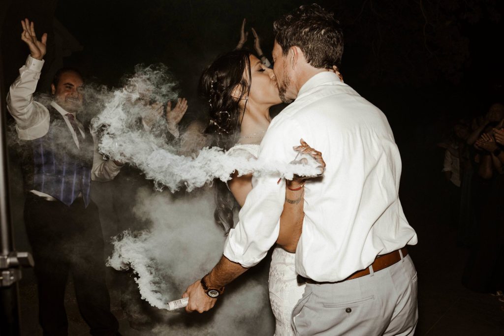 Wedding couple kissing while surrounded by smoke at the elm estate