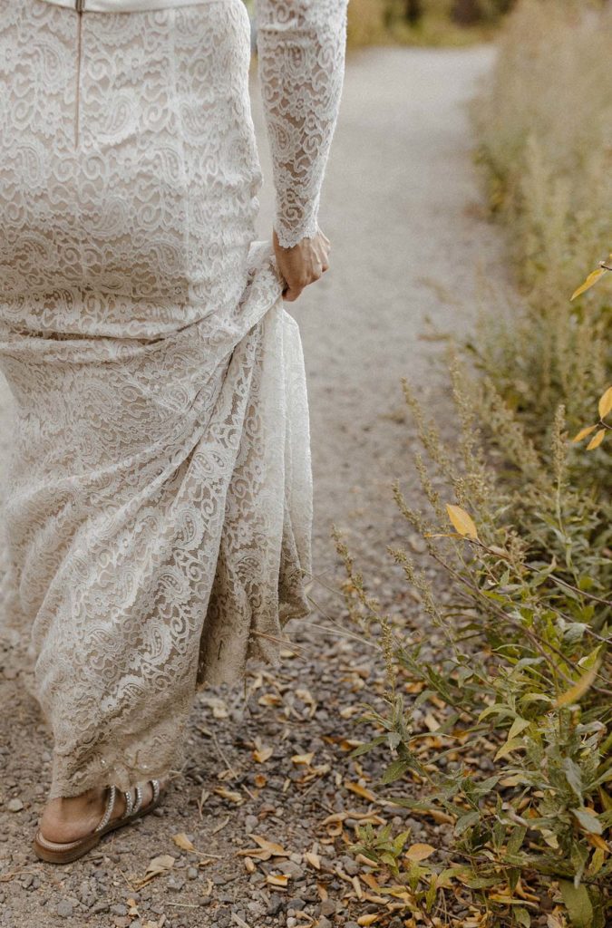 bride holding her dress walking by greenery in lake tahoe