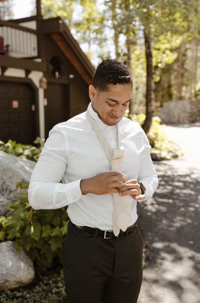 groom tying his tie at the resort at squaw creek
