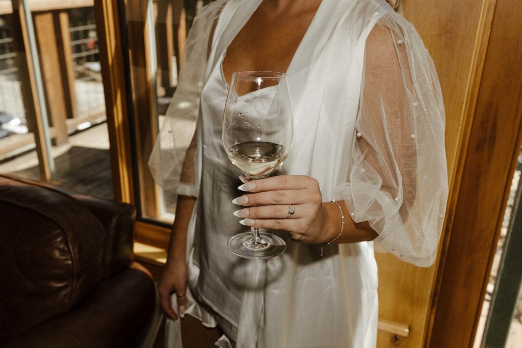 bride holding a champagne glass while getting ready at the resort at squaw creek