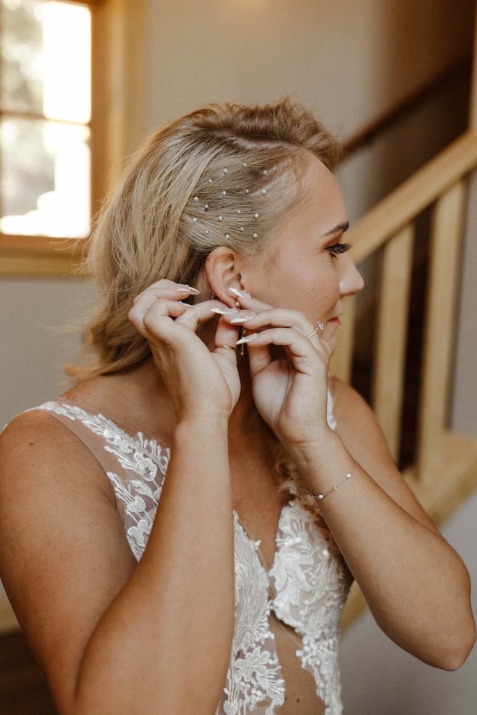 bride putting on her pearl earrings on her wedding day at the resort at squaw creek