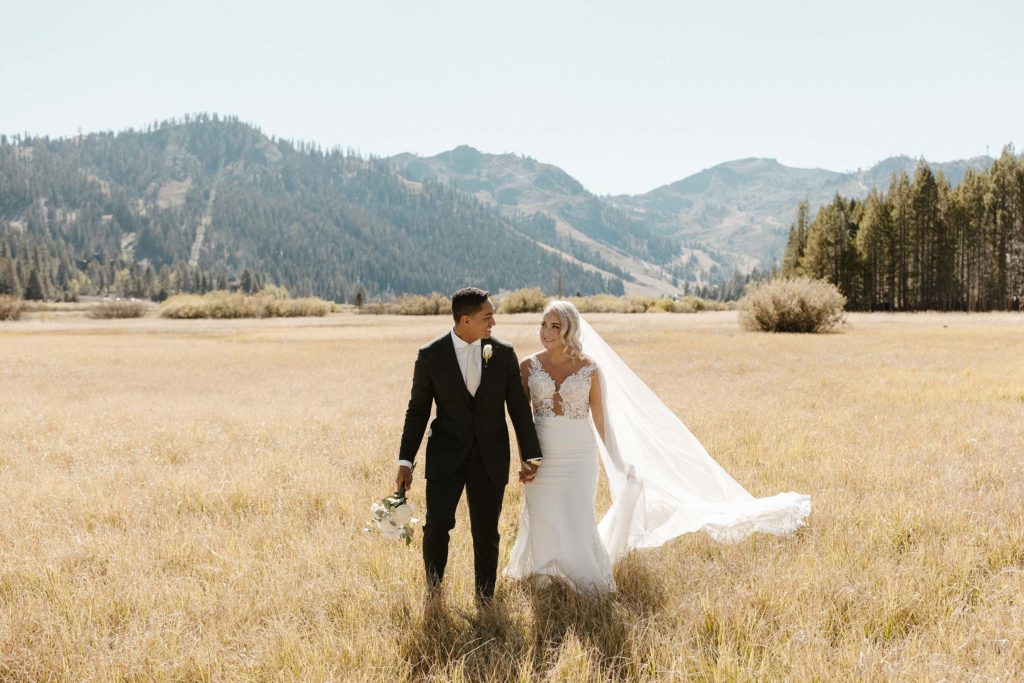 wedding couple walking in a golden meadow at the resort at squaw creek