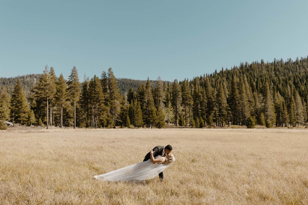 wedding couple doing the dip kiss pose in a golden meadow at the resort at squaw creek