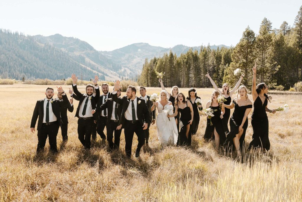 wedding party cheering in a golden meadow at the resort at squaw creek