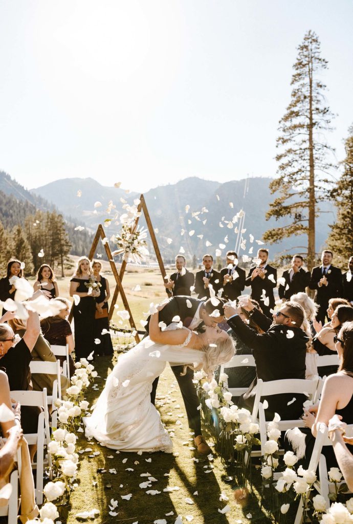 bride and groom kiss with flower petals falling in front of them at the resort at squaw creek