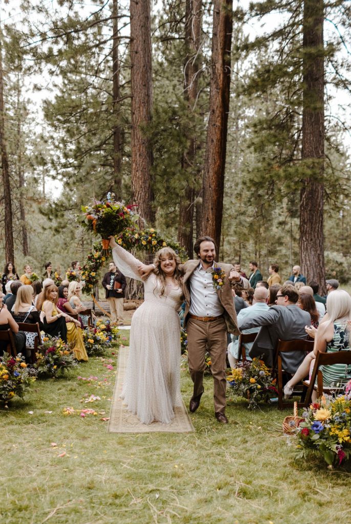 Wedding couple celebrating while walking down aisle after ceremony with guests cheering outside in Lake Tahoe