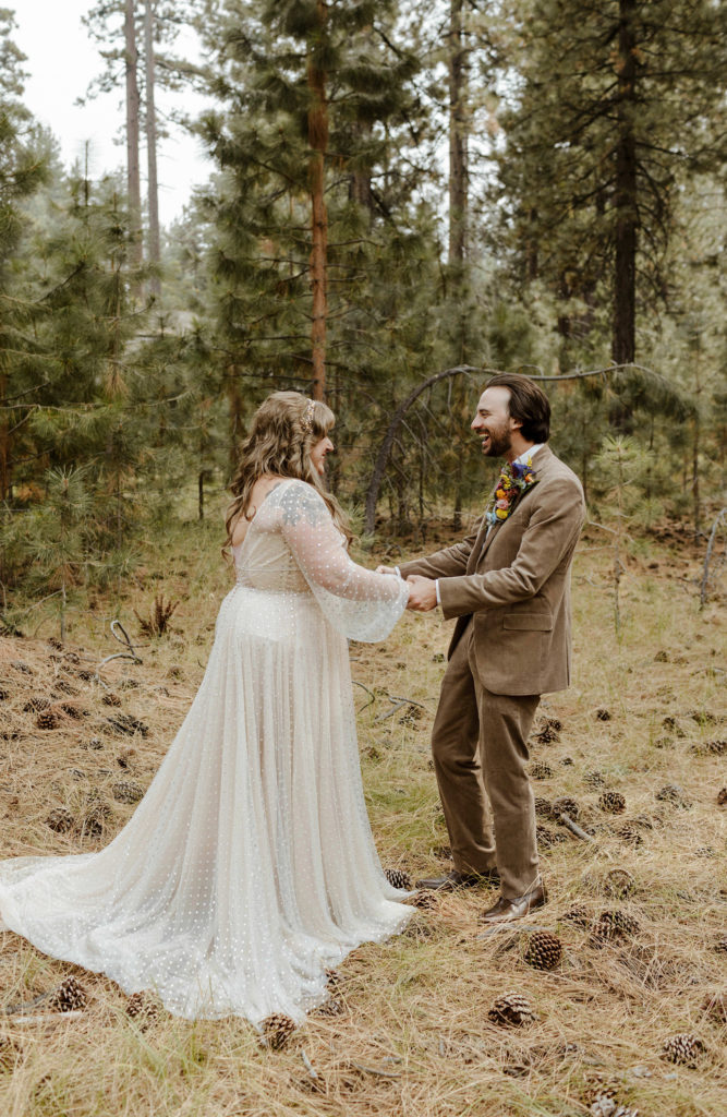 Wedding groom excited and holding hands with bride during first look in forest in Lake Tahoe