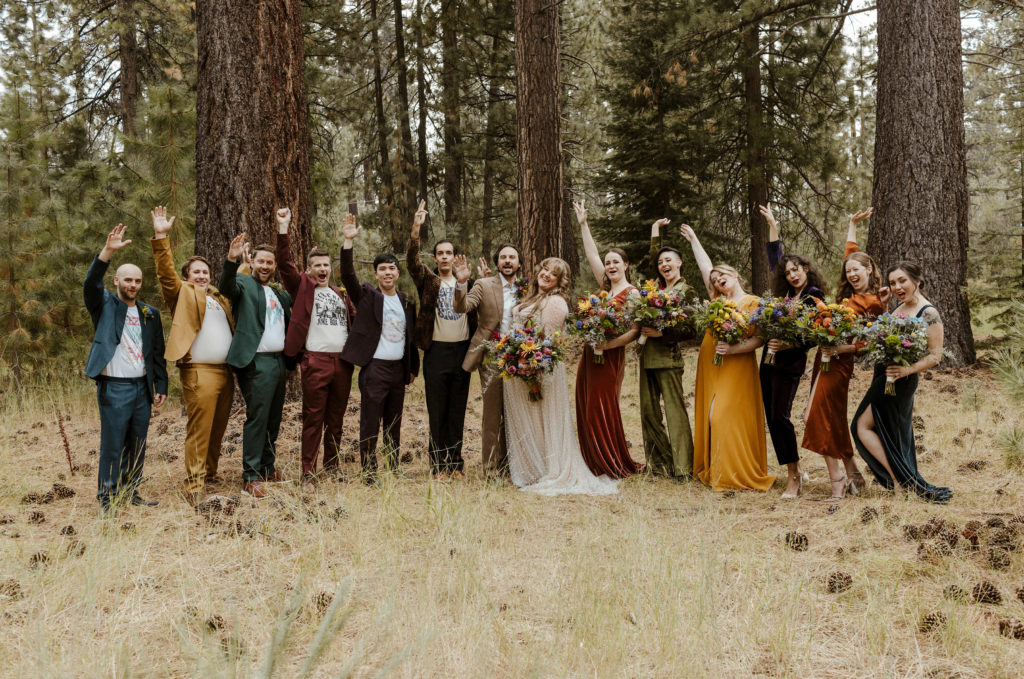 Wedding couple and wedding party celebrating while standing together in forest in Lake Tahoe