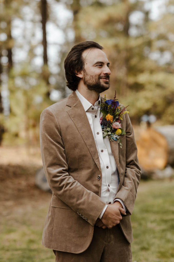 Wedding groom smiling while standing with hands clasped at wedding ceremony in Lake Tahoe