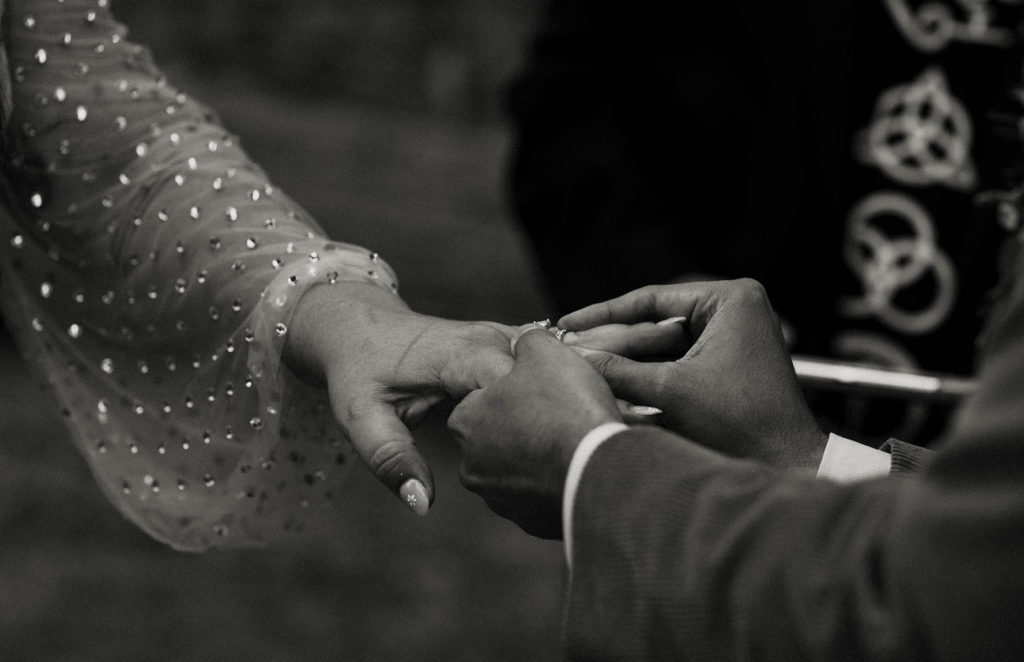 Close up of groom sliding wedding ring onto finger of bride during wedding ceremony outside in Lake Tahoe